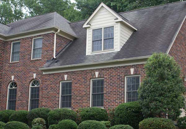 Suburban brick home with aging roof showing signs of wear