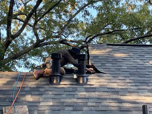 Roofer inspecting pipe boots and vents on residential roof
