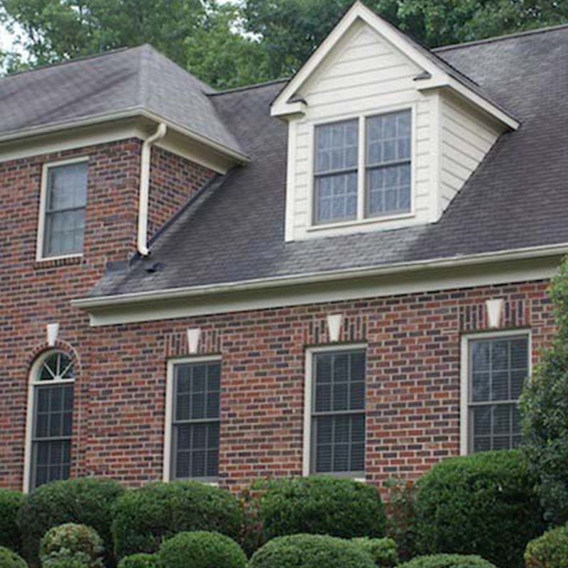 Two-story brick home with shingle roof and dormer